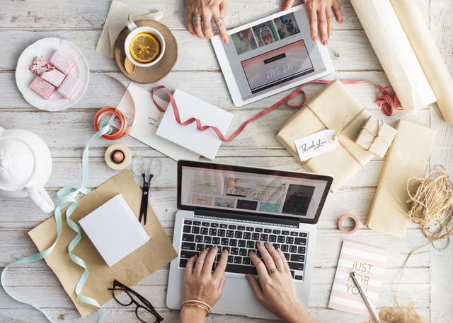 Someone doing work on their laptop with a clutter around them.