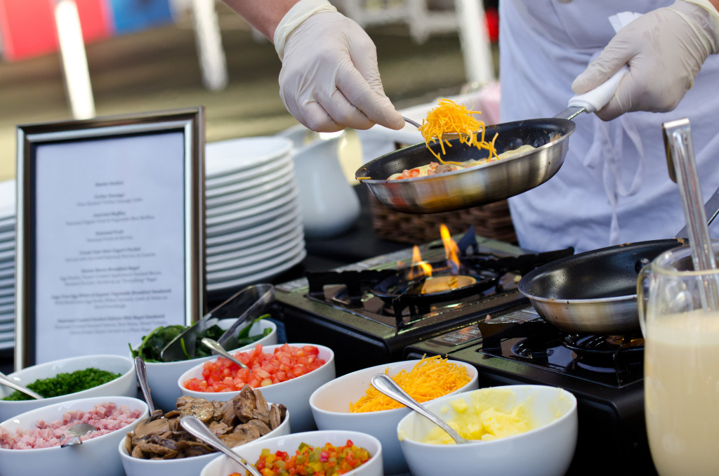 A chef preparing an omelet with different toppings in front of him.