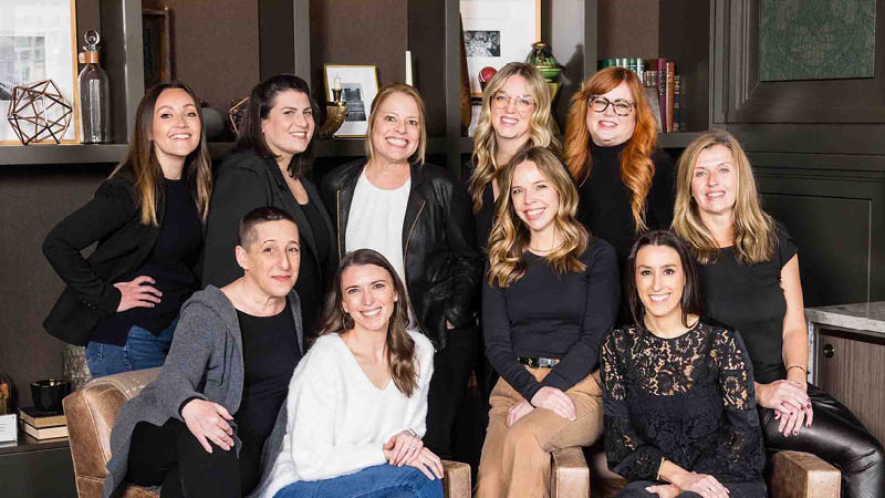 Meet the Catered Events Team - Blue Plate's sales team sitting and smiling around a table.