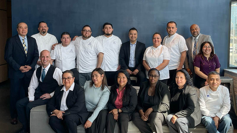 Meet the Event Operations Team - Blue Plate's event operations team standing and smiling in front of a blue wall.