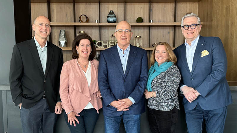 Meet the Executive Leadership Team - Blue Plate's executive leadership team standing and smiling in front of a built-in bookcase.