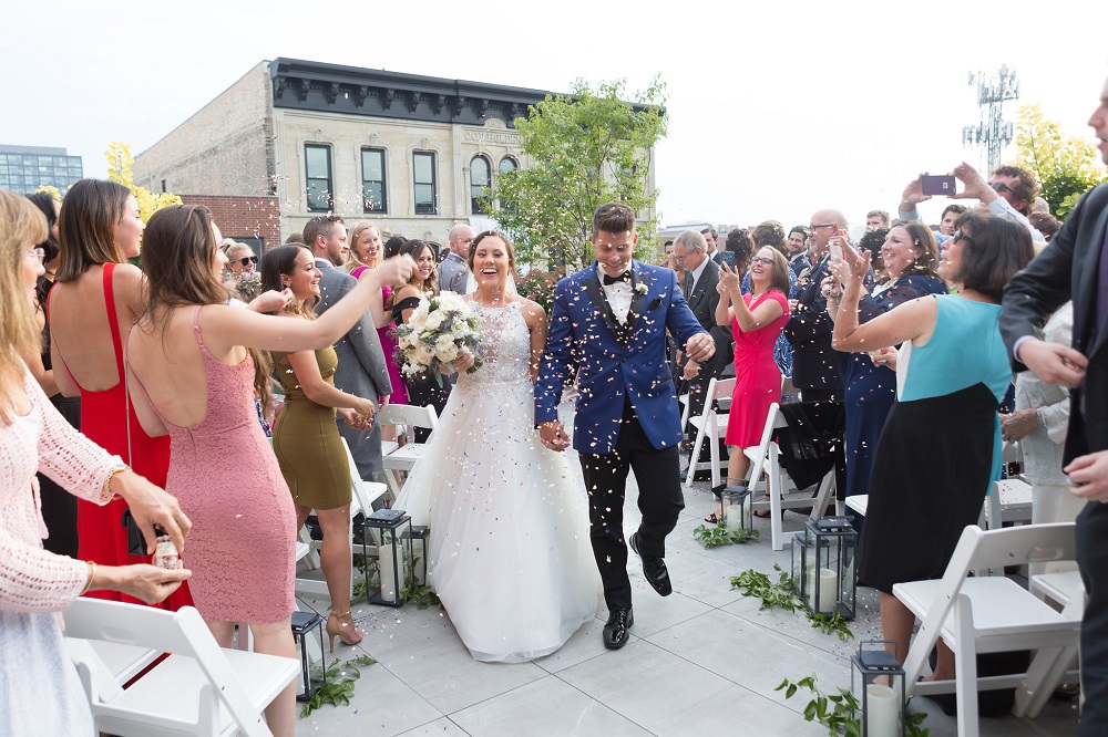 Bride and groom walking back up the aisle with friends and family cheering for them